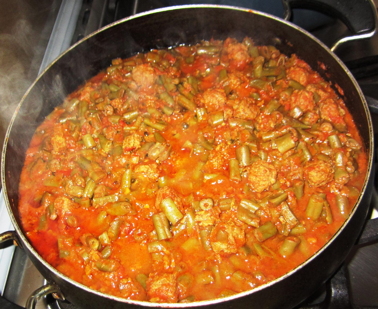 Ragoût de haricots verts et de viande à la tomate, en cuisson dans sa casserole