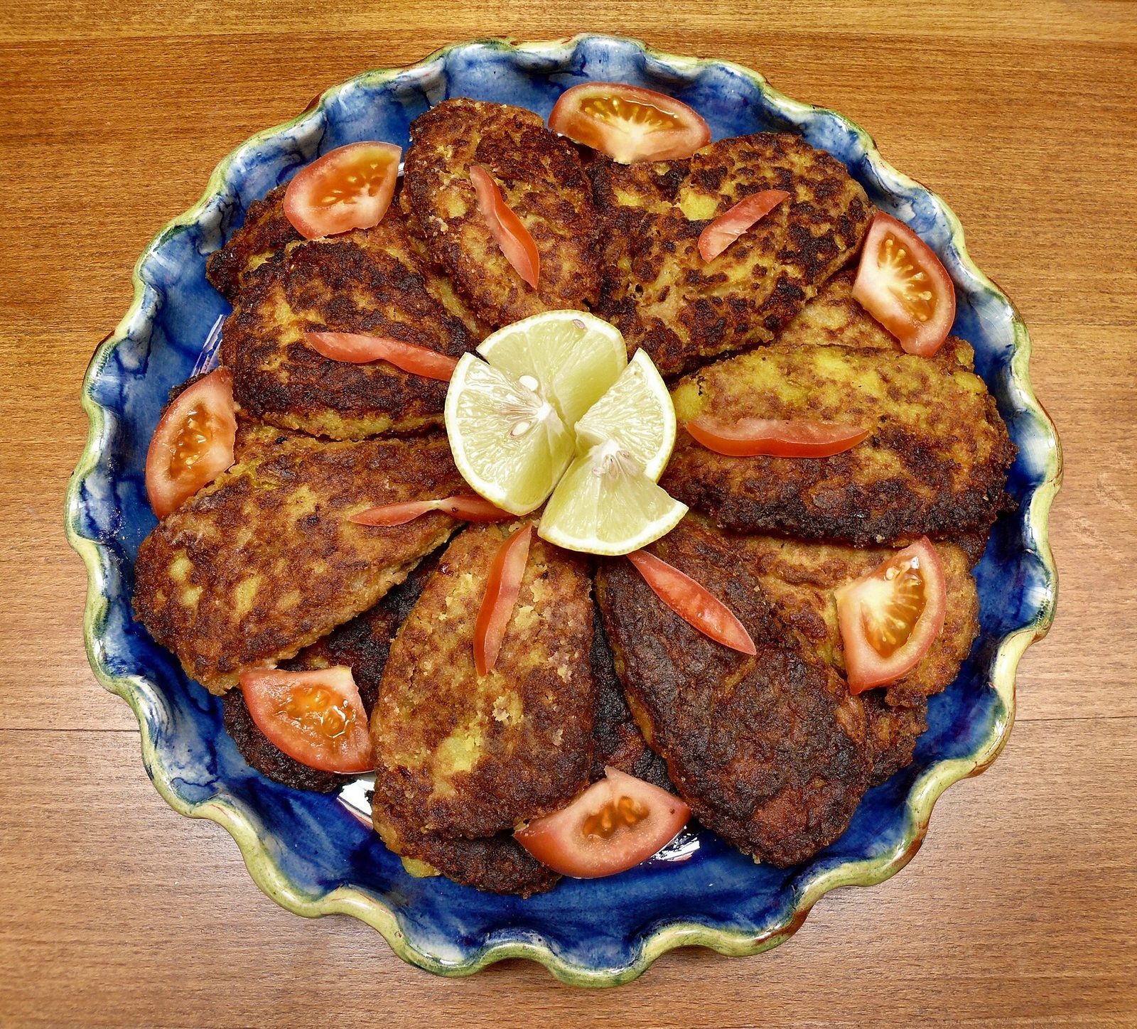 Plat de kotlets iraniens : croquettes ovales de pomme de terre et de viande dorées à la poêle, avec citron et quartiers de tomate